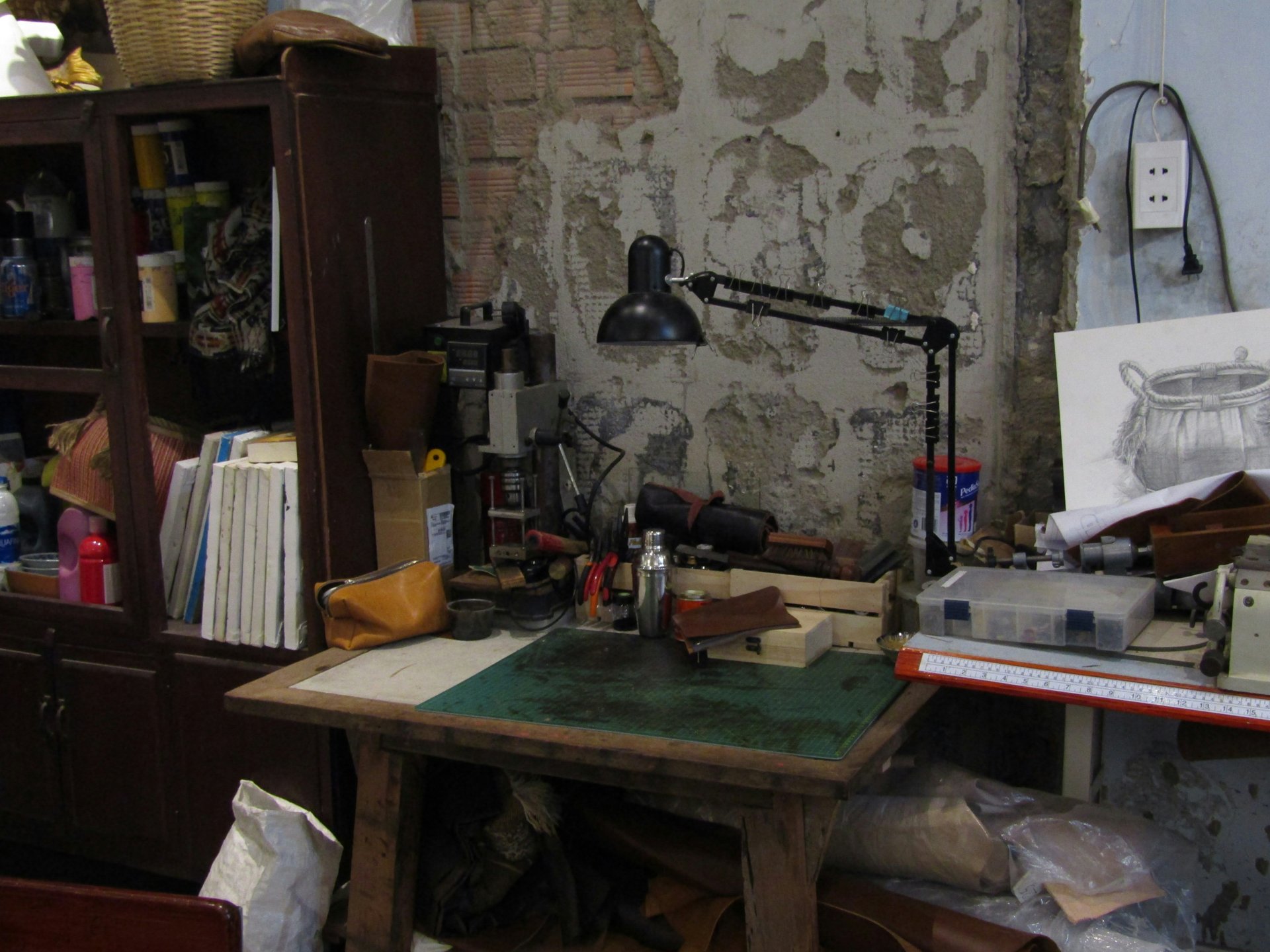 Rustic workbench with tools, leather goods, and crafting materials in warm light