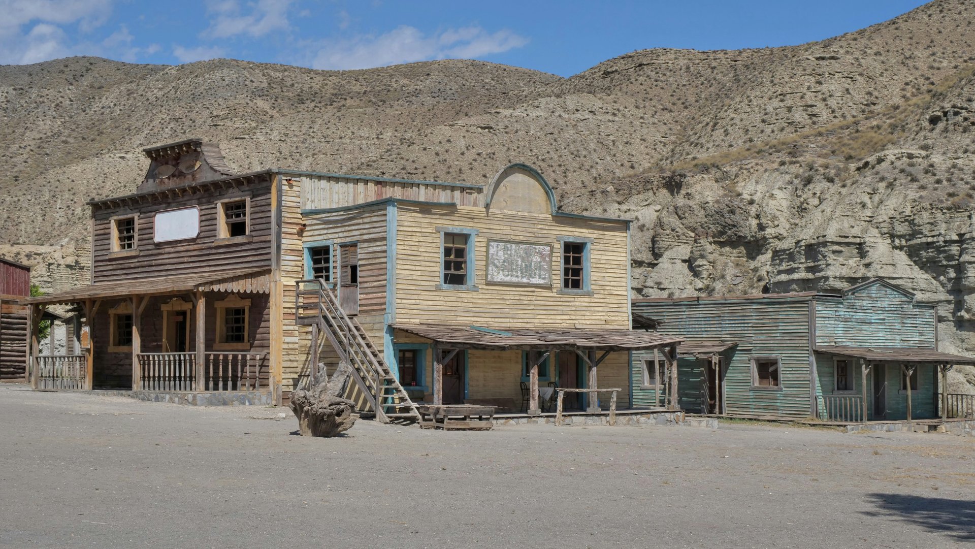 Wide open western landscape with dusty trail leading to a small frontier town